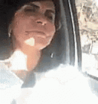 a woman is sitting in a car looking out the window .