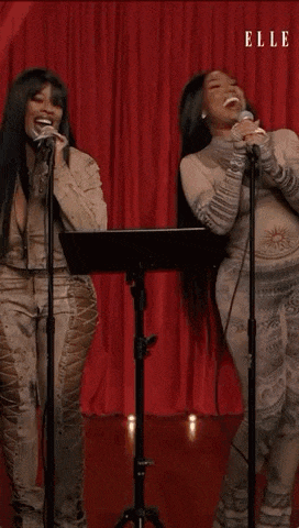 a couple of women are singing into microphones on a stage .