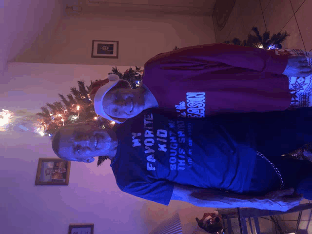 a man wearing a shirt that says " my favorite kid " stands next to another man