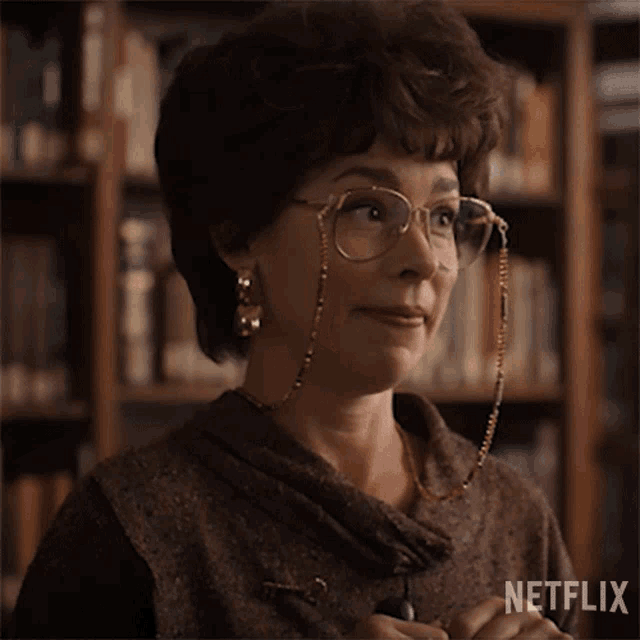 a woman wearing glasses and earrings is making a funny face .