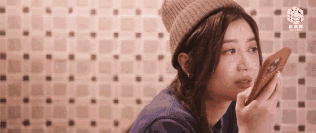 a woman wearing a beanie looks at herself in a mirror
