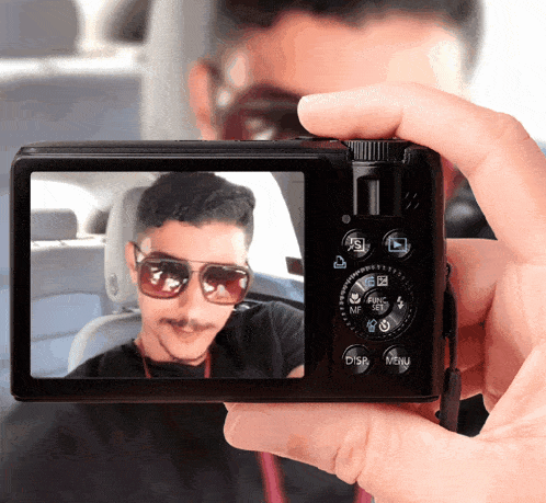 a person taking a picture of a man wearing sunglasses with a menu button