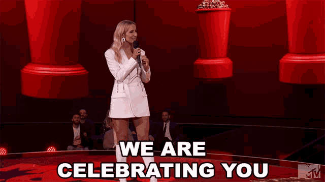 a woman speaking into a microphone with the words " we are celebrating you " behind her