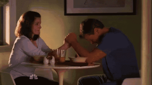 a man and a woman are sitting at a table holding hands