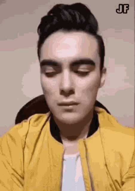 a man in a yellow jacket is making a funny face .