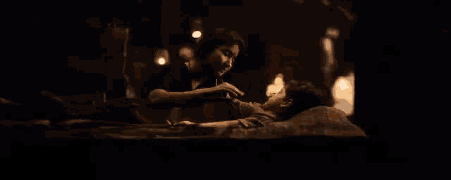 a man and woman are laying on a bed in a dark room .