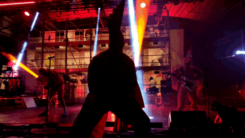 a man in a hoodie is standing on a stage with a guitar