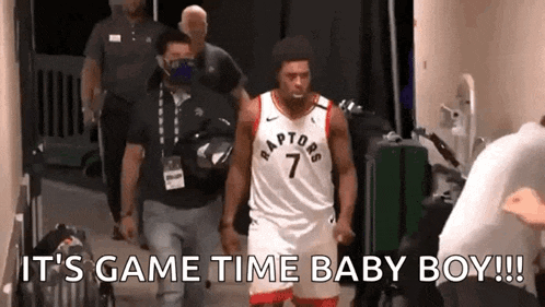 a man in a raptors jersey is walking down a hallway with a man in a mask behind him .