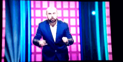 a man in a blue suit is standing in front of a pink and blue background