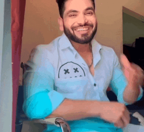 a man with a beard is wearing a shirt with a smiley face on the pocket