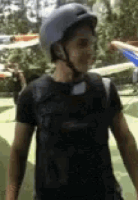 a man wearing a helmet and a black shirt is standing on a green field .