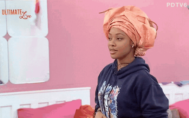 a woman wearing a turban stands in front of a pink wall that says ultimate love on it