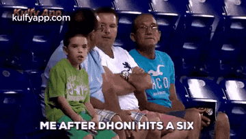 a group of people are sitting in a stadium and one of them is saying me after dhoni hits a six .