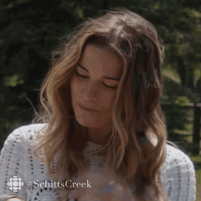 a close up of a woman 's face with #schittscreek written on the bottom