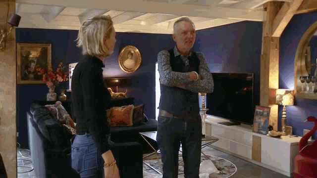 a man and a woman standing in a living room talking