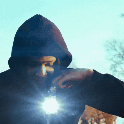 a man in a hooded jacket has a light shining on his face that says ' netflix '