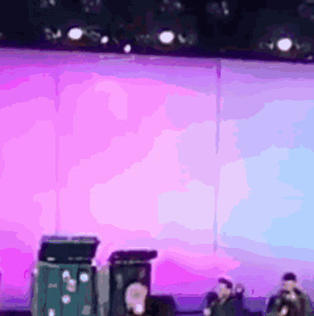 a blurry picture of a band on stage with a pink background