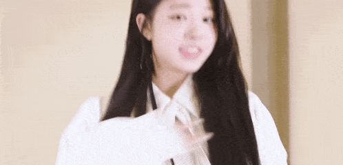 a young woman with long black hair is wearing a white shirt and tie and smiling .