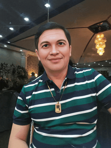 a man wearing a striped shirt with a gold pendant on his neck