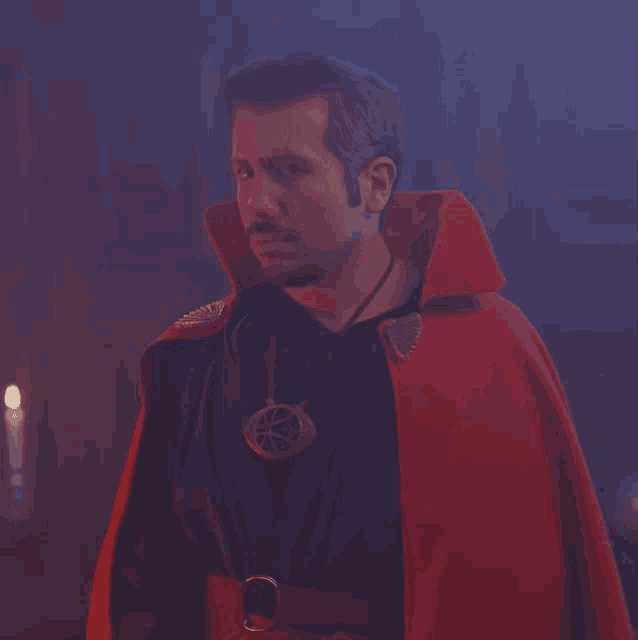 a man wearing a red cape and a necklace with a circle on it