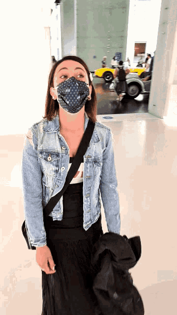 a woman wearing a mask and a denim jacket looks up
