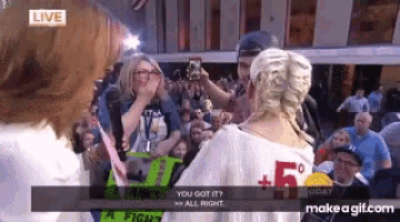 a woman is standing in front of a crowd of people taking a picture of her .
