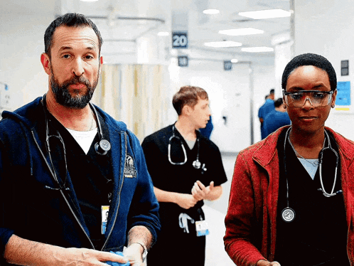 a man and a woman standing in a hospital hallway with the number 20 on the wall