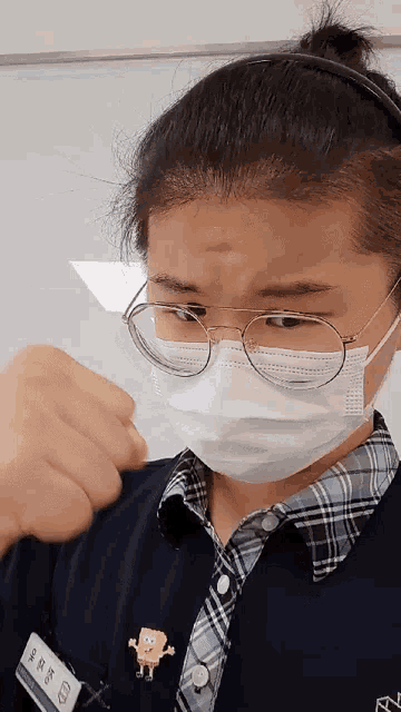 a woman wearing a face mask and glasses has a spongebob pin on her shirt