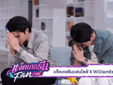 two men are praying in front of a fan live banner