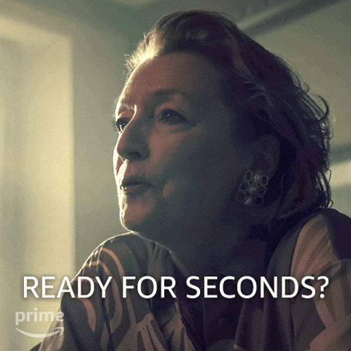 a woman is sitting in front of a sign that says ready for seconds on it