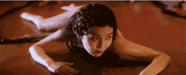 a naked woman is crawling on the floor in a dark room .