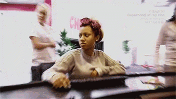 a woman is sitting at a desk in front of a sign that says " superhero of hip hop "