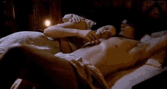 a man and a woman are laying on a bed . the man is naked and the woman is wearing a wedding ring .