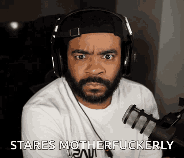 a man wearing headphones says stares motherfuckerly in front of a microphone