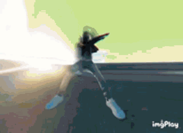 a person is jumping in the air with their arms outstretched in a gif .