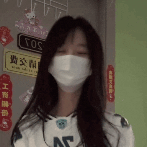 a woman wearing a face mask is standing in front of a sign that says cos