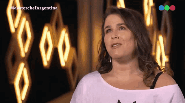 a woman stands in front of a sign that says masterchefargentina