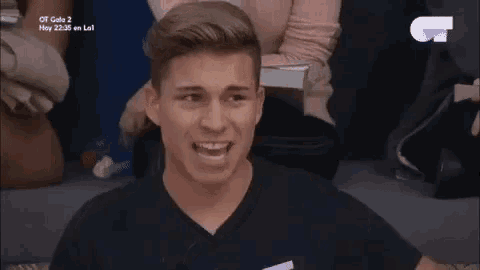 a man in a black shirt is laughing while sitting in a chair .
