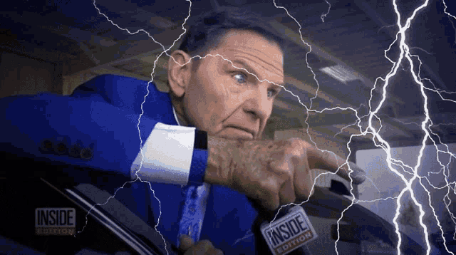 a man in a blue suit is holding a sign that says inside edition on it