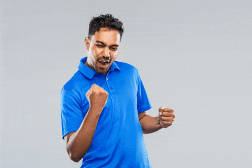 a man in a blue shirt holds his fist in the air
