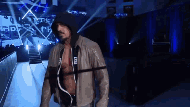 a man in a hooded jacket is walking down a staircase in a stadium .