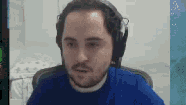 a man wearing headphones and a blue shirt is sitting in a chair .