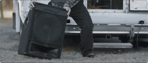 a man is carrying a large speaker in front of a white van