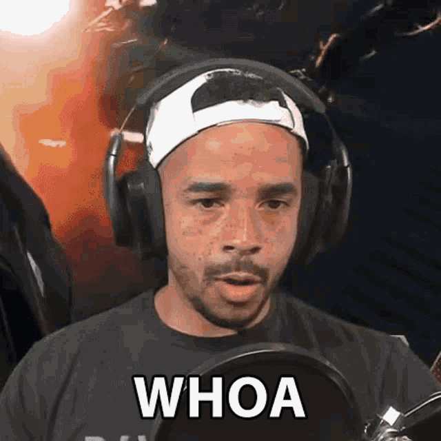 a man wearing headphones and a baseball cap is saying whoa