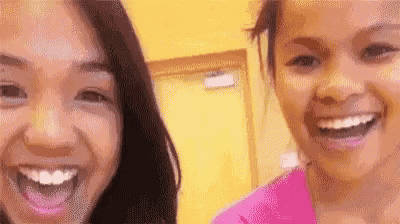 two young women are smiling for the camera while standing next to each other in a room .