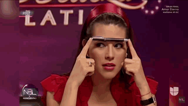 a woman is holding a pen to her forehead in front of a sign that says ' lati '