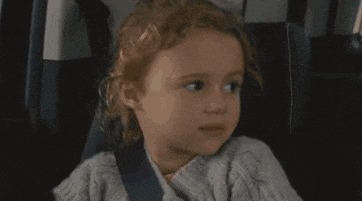 a little girl is sitting in the back seat of a car .