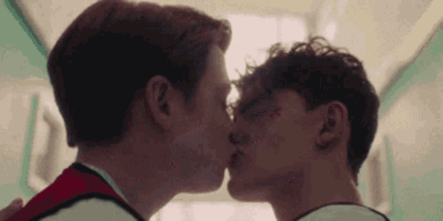 two young men are kissing in a hallway in a hospital .