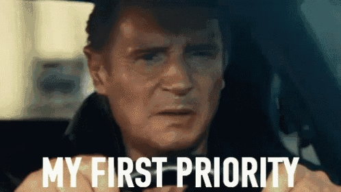 a man is sitting in a car with the words `` my first priority '' written on the screen .