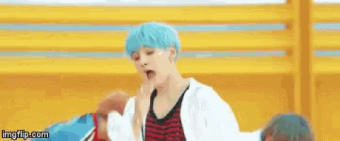 a young boy with blue hair is singing into a microphone while standing in front of a yellow wall .